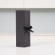 A plain black crafted gift box with a black bow against a pale grey background. A plain black crafted gift box with a black bow against a pale grey background.